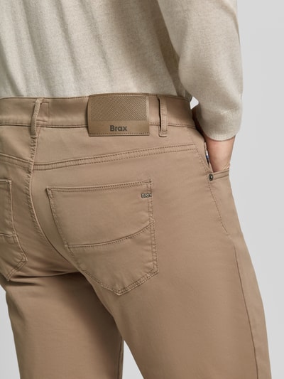 Männermodel trägt Regular Fit Weite Hose aus Baumwoll-Mix mit Lyocell-Anteil von Brax in Beige, Textur glatte Baumwolle, Nahaufnahme Rückansicht, Herren Weite Hose von Brax