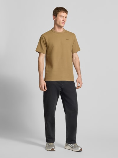 Męski model nosi Regular Fit T-Shirt mit Strukturmuster von G-Star Raw w kolorze beżowym, okrągły dekolt, logo, długość tyłu w rozmiarze M: 71 cm, fakturowany wzór, widok całej sylwetki z przodu
