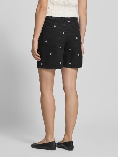 Frauenmodel trägt Schwarze Jeansshorts mit Stitchings von REVIEW aus reiner Baumwolle, Regular Fit, schwarze Farbe, sichtbare Nähte, Taschen und gestickte Muster, Ganzkörperansicht Rückansicht.