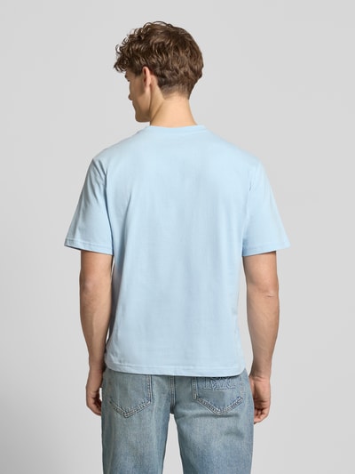Männermodel trägt Basic T-Shirt mit kleinem Logo-Patch auf der Brust von REVIEW in Hellblau, reine Baumwolle, gerader Schnitt, Ganzkörperansicht Rückansicht
