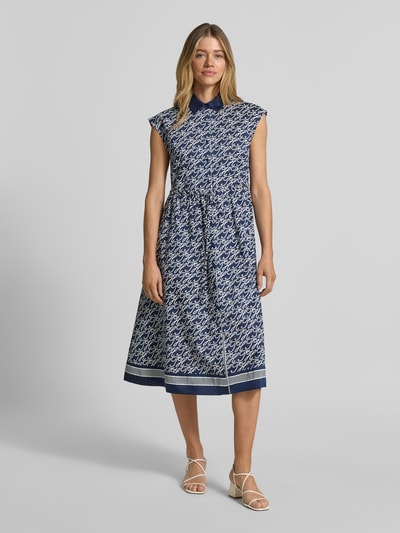 Frauenmodel trägt Hemdblusenkleid in Midi-Länge aus Baumwolle-Seide-Mix von Tommy Hilfiger, Allover-Muster, tailliert, Knopfleiste, Ohne Ärmel, Ganzkörperansicht von vorne