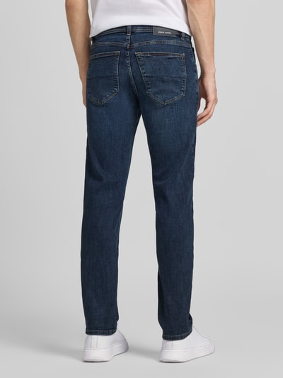Mężczyznamodel nosi Jeans mit Eingrifftaschen Modell 'Dijon' von Pierre Cardin w kolorze ciemnoniebieskim, krój slim fit, mieszanka bawełny z dodatkiem streczu, wpuszczane kieszenie, szerokość w rozmiarze 32/32: 39 cm, długość wewnętrzna nogawki: 78 cm, całkowita sylwetka z tyłu.
