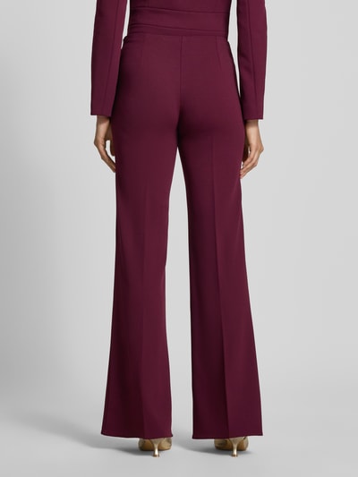 Frauenmodel trägt Flared Fit Stoffhose mit Bügelfalten von Rinascimento in dunklem Rot, elastischer Bund, glatte Textur, Ganzkörperansicht Rückansicht.