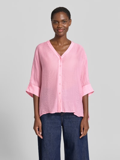 Frauenmodel trägt Relaxed Fit Bluse aus Viskose-Mix mit 3/4-Arm von Comma in Rosa mit V-Ausschnitt und Knopfleiste, Ganzkörperansicht von vorne. Rückenlänge 62 cm, Ärmellänge 18 cm, strukturierte Oberfläche.