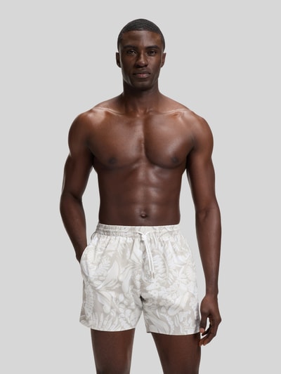 Männermodel trägt Regular Fit Badeshorts mit Allover-Muster Modell 'PIRANHA' von BOSS, florales Muster, elastischer Bund mit Tunnelzug, Taschen; Optik:Allover-Muster, Label-Patch sichtbar, Ganzkörperansicht von vorne.