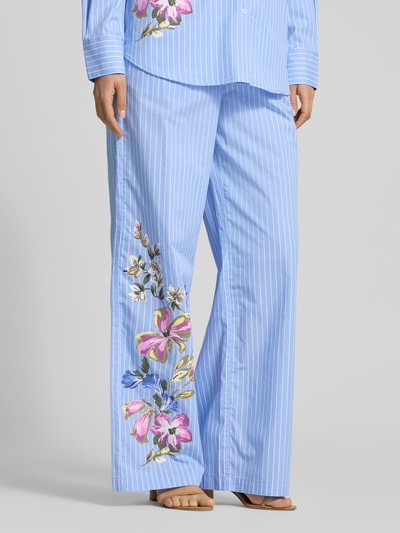 Frauenmodel trägt Wide Fit Stoffhose mit floralem Print von Fynch-Hatton aus reiner Baumwolle, elastischer Bund mit Tunnelzug, blauer Stoff mit weißen Streifen und buntem Floraler-Print, Bundweite 34 cm, Innenbeinlänge 78 cm; Ganzkörperansicht von vorne.