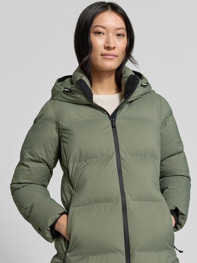 Kobiece modelka nosi płaszcz Regular Fit Model 'TANARE' w zielonym kolorze z efektem pikowania od khujo, naszywka z logo, zamek błyskawiczny dwustronny, Nahaufnahme Oberkörper. Długość tyłu w rozmiarze S: 82 cm, szerokość ramion w rozmiarze S: 47 cm, szerokość w klatce piersiowej w rozmiarze S: 47 cm, długość rękawa w rozmiarze S: 59 cm.