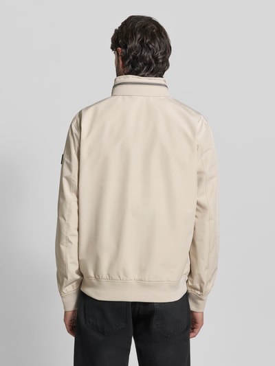 Männermodel trägt Regular Fit Jacke mit Kapuze von NAUTGÅRD in Beige, glatte Oberfläche, Stehkragen, Rückenansicht, Ganzkörperansicht.