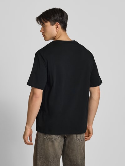 Männermodel trägt Oversized T-Shirt Modell 'FISHER' von Blend in Schwarz aus reiner Baumwolle, Rückenansicht, Ganzkörperansicht Rückansicht.