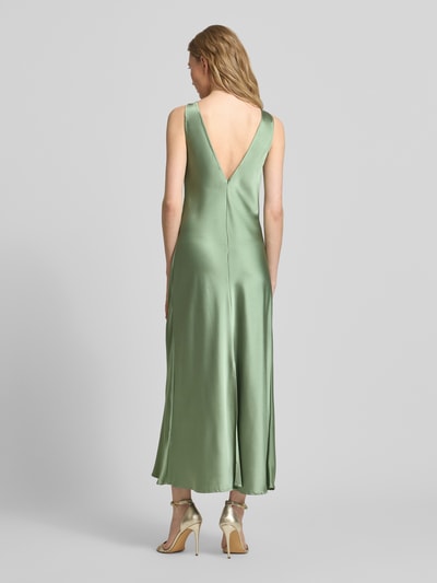 Frauenmodel trägt Cocktailkleid mit tiefem Rückenausschnitt von GUIDO MARIA KRETSCHMER WOMAN aus grünem Satin, Midikleid, körpernaher Schnitt, breite Träger, V-Ausschnitt hinten, fließende Textur, Ganzkörperansicht Rückansicht.