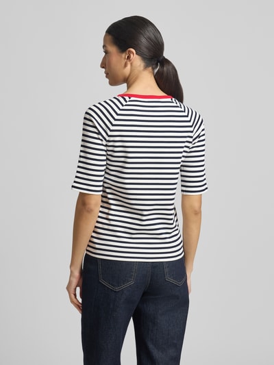 Modelka kobieca ma na sobie Shaped Fit T-Shirt aus reiner Baumwolle od Tom Tailor Denim, biało-granatowe paski, krótki rękaw, okrągły dekolt, label stitching i serduszko, dzianina w drobny prążek, widok całej sylwetki od tyłu.