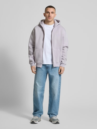 Männermodel trägt Sweatjacke mit Känguru-Tasche von REVIEW im Relaxed Fit aus Baumwoll-Mix in Hellgrau, Ganzkörperansicht von vorne.