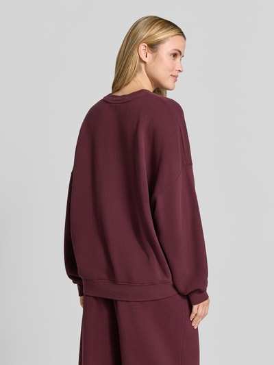 Frauenmodel trägt Oversized Fit Sweatshirt aus Baumwoll-Mix mit Stretch-Anteil von American Vintage in Dunkelrot, elastische Bündchen, Ganzkörperansicht Rückansicht.