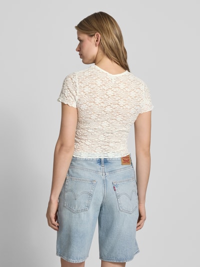 Frauenmodel trägt Slim Fit T-Shirt aus Spitze Modell 'FAITH' von Only in Unifarbe mit Spitzenmuster, Rundhals und kurzen Frillärmeln, Ganzkörperansicht Rückansicht.