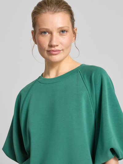Frauenmodel trägt Oversized Sweatshirt mit Ballonärmeln von BOSS Orange in einfarbigem Grün, Rundhals, Nahaufnahme Oberkörper.