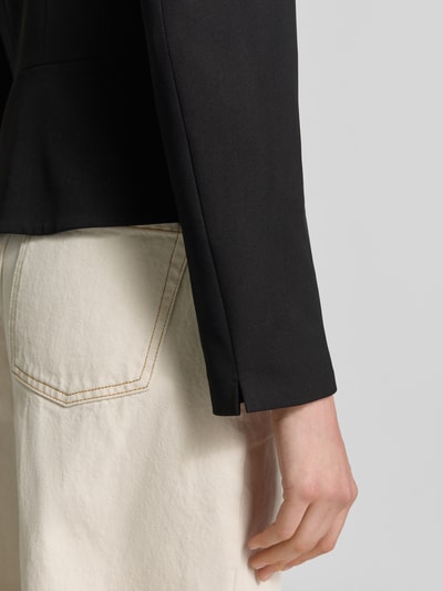 Kobieta modelka nosi Slim Fit Blazer mit Hakenverschluss od Christian Berg Woman Selection, mieszanka materiałów z dodatkiem wiskozy, czarna tkanina, kremowe spodnie, szczegółowy widok na rękaw i kieszeń, detailaufnahme ręki.