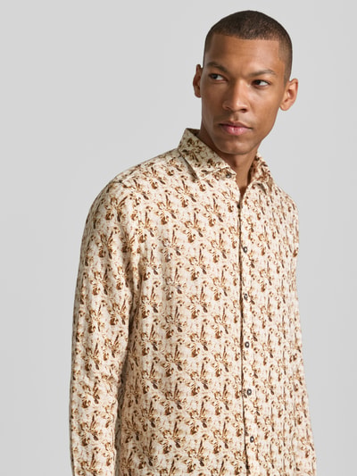 Männermodel trägt Slim Fit Freizeithemd aus reinen Leinen Modell 'Gold' von bugatti mit floraler Allover-Print, Kentkragen, durchgängige Knopfleiste, cremebraune Farben, feine Textur, Langärmelig, Nahaufnahme Oberkörper, Rückenlänge 78 cm, Schulterbreite 45 cm, Ärmellänge 68 cm.