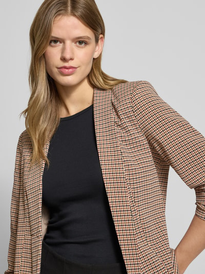 Kobiece modelka nosi Regular Fit Longblazer mit Allover-Muster Modell 'BOSELLA' od Pieces, efekt: wzór na całej powierzchni, krój regular fit, kołnierz z połami, poduszki na ramionach, rękaw o dł. 3/4, zakończenie rękawów marszczone, wykończenie materiału: tkana faktura, półzbliżenie górnej części ciała.