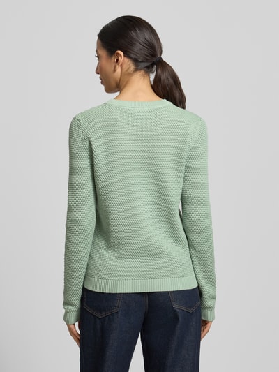 Frauenmodel trägt Strickpullover mit gerippten Abschlüssen Modell 'dalo' von Vila in Hellgrün, Baumwolle, Strukturstrick, Rückansicht.