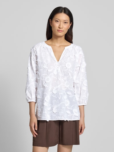 Frauenmodel trägt Regular Fit Bluse mit V-Ausschnitt und 3/4-Arm von Comma im Material-Mix mit Baumwoll-Anteil, Stitchings, weiße florale Textur, Rückenlänge 68 cm bei Größe 36, Nahaufnahme Oberkörper.