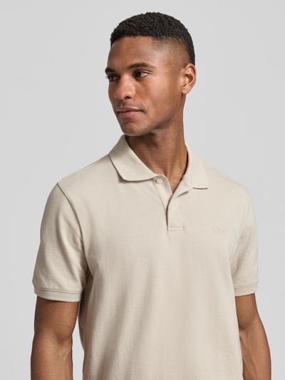 Männermodel trägt Slim Fit Poloshirt mit Label-Stitching von GAP in Beige, Baumwoll-Elasthan-Mix, Nahaufnahme Oberkörper.