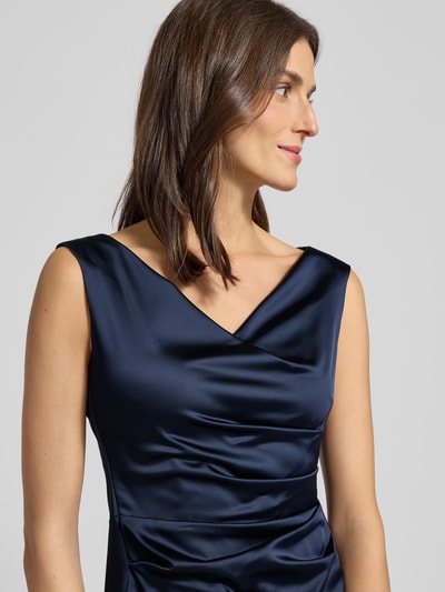 Frauenmodel trägt Cocktailkleid mit Wasserfall-Ausschnitt von Vera Mont in dunkelblauem Material-Mix mit Stretch-Anteil, Nahaufnahme Oberkörper. Taillierter Schnitt, ärmelloses Design, Nahtreißverschluss, Unterkleid, Rückenlänge 93 cm, Brustweite 47 cm bei Größe 38.