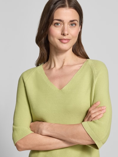 Kobiece model nosi Regular Fit Strickpullover aus Baumwoll-Mix od s.Oliver RED LABEL, jednolity kolor, mieszanka bawełny, dekolt w serek, krótki rękaw, raglanowe rękawy, wykończenie prążkowane, aplikacja z logo z metką z metalu, dzianina; zbliżenie na górną część ciała z przodu.