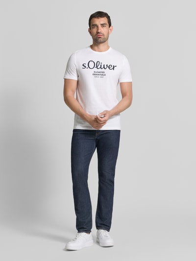 Męski model nosi Regular Fit T-Shirt aus reiner Baumwolle Modell 'BASIC TEE BIG LOGO' von s.Oliver RED LABEL, białe z czarnym nadrukiem, gładka faktura, proste kształty, Ganzkörperansicht von vorne.