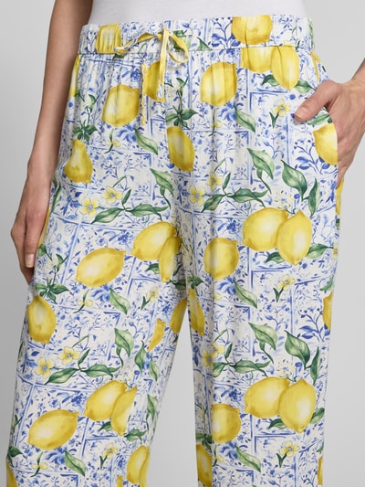 Frauenmodel trägt Caprihose aus Viskose im Allover-Look von Christian Berg Woman, entspannter Schnitt, gelbe Zitrusmotive, Nahaufnahme Oberkörper.