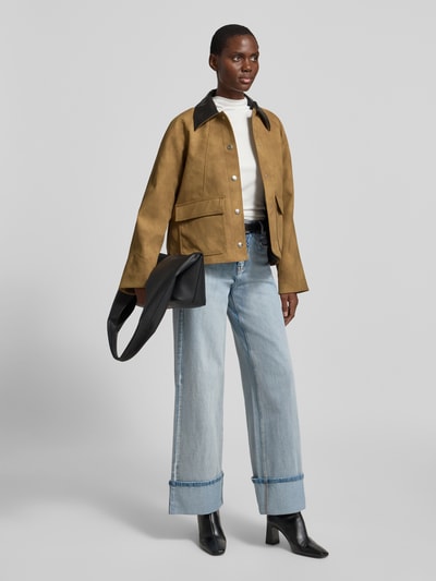 Frauenmodel trägt Regular Fit Jacke mit Umlegekragen Modell 'Wilhelmina' von STAND STUDIO in Leder-Optik, sand, aufgesetzte Taschen, silberne Knöpfe, lockere Passform, helle Jeans, schwarze Stiefeletten, glatte Textur; Ganzkörperansicht von vorne.