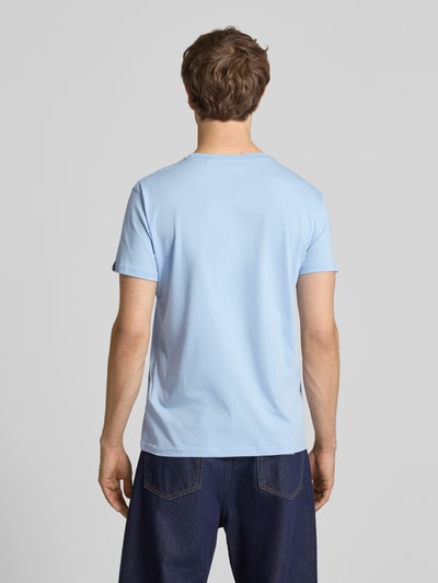 Mężczyzna nosi T-Shirt mit Label-Detail od Alpha Industries w jasnoniebieskim kolorze, bawełna, krój prosty, widok całej sylwetki z tyłu.