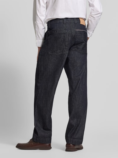 Männermodel trägt Relaxed Fit Jeans aus reiner Baumwolle von ANNARR in Dunkelblau, strukturierte Oberfläche, Eingriff- und Gesäßtaschen, Ganzkörperansicht Rückansicht.