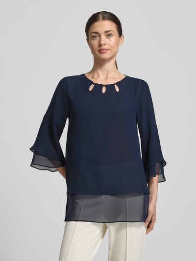Frauenmodel trägt Regular Fit Blusenshirt aus fließendem Stoff von Vera Mont, dunkelblauer Chiffon, Stufen-Look, 3/4-Arm, Ganzkörperansicht von vorne.