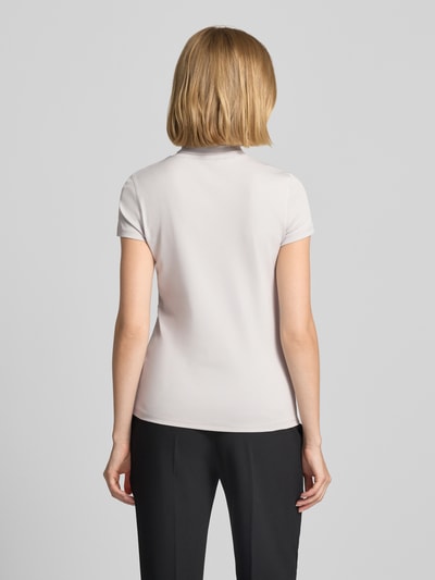 Frauenmodel trägt Slim Fit T-Shirt mit hochschließendem Polokragen von Marc Cain aus Baumwoll-Elasthan-Mix in Hellbeige, Rückenansicht.