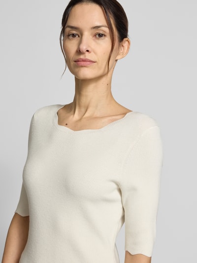 Frauenmodel trägt Strickshirt aus Viskose-Mix mit Rüschenkragen von Christian Berg Woman in Creme, taillierte Passform, Nahaufnahme Oberkörper.