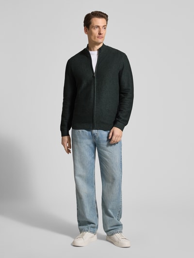 Męski model nosi Regular Fit Cardigan mit Stehkragen od OLYMP Level Five, czysta bawełna, krój regular fit, dzianinowa faktura, suwak, elastyczne wykończenia, długość tyłu 68 cm, długość rękawa 67 cm, widok całej sylwetki z przodu.