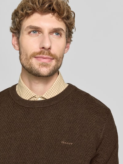 Männermodel trägt braunen Regular Fit Pullover aus Baumwoll-Woll-Mix von GANT, dezentes Muster, weiche Textur, Nahaufnahme Oberkörper.