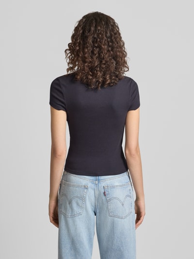 Frauenmodel trägt T-Shirt mit Rundhalsausschnitt Modell 'PREPPY HEART' von Review, schwarz, gerader Schnitt, Feinripp, Rückansicht, Ganzkörperansicht.