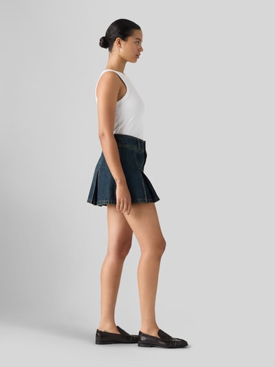 Frauenmodel trägt Ausgestellter Mini-Rock aus reiner Baumwolle von Levi's®, dunkles Blau, klare Linien, strukturierte Oberfläche, Ganzkörperansicht von der Seite, Damen Mini-Rock von Levi's®.