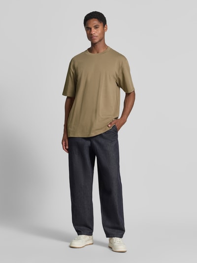 Męski model nosi Oversized T-Shirt aus reiner Baumwolle od Lindbergh w kolorze khaki, krój oversized, półrękaw, Długość tyłu w rozmiarze M: 70 cm, Ganzkörperansicht von vorne.