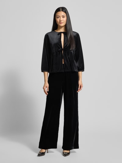 Kobiece modelka nosi spodnie materiałowe z elastycznym pasem Model 'Mucia' od OPUS Pants, luźny krój, czarne, wpuszczane i tylne kieszenie, widok całej sylwetki z przodu.