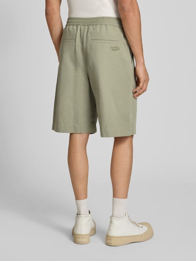 Männermodel trägt Shorts aus Baumwoll-Mix von MAISON KITSUNÉ in hellem Grün, Regular-Fit, Elastischer Bund, Eingrifftaschen, Knielänge, Bundweite 41 cm, Innenbeinlänge 24 cm, Ganzkörperansicht Rückansicht.