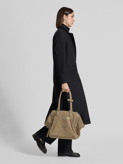 Frauenmodel trägt Satchel Bag mit Label-Prägung Modell 'KAYLA' von LIEBESKIND BERLIN in Beige, strukturierte Oberfläche, Ganzkörperansicht von der Seite. Damen Satchel Bag mit Reißverschluss und langen Tragegriffen, Außentasche und 60 cm Schulterriemen, 58x32x20 cm.