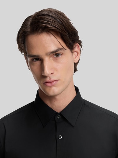 Männermodel trägt Slim Fit Freizeithemd aus Baumwoll-Mix Modell 'ERMO' von HUGO in Schwarz, Kentkragen, unifarben, Nahaufnahme Oberkörper.