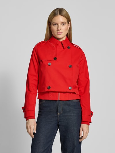 Vrouwenmodel draagt 'Trenchcoat mit Ärmelriegeln' van monari in felrood, regular fit, knoopsluiting, detailopname bovenlichaam.