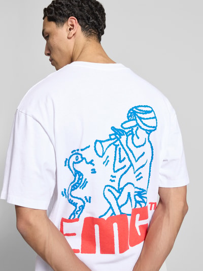 Mężczyznamodel nosi męski t-shirt z bawełny model 'CHARMER' od Edwin, prosty krój, okrągły dekolt, długość tyłu w rozmiarze M: 70 cm, białe i kolorowe nadruki, widok na plecy, całkowity tył.