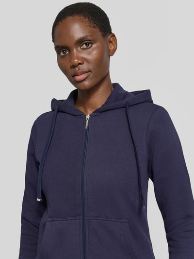 Frauenmodel trägt Regular Fit Sweatjacke aus Baumwoll-Mix von Christian Berg Woman in Dunkelblau, mit Kapuze und Känguru-Tasche, Nahaufnahme Oberkörper.