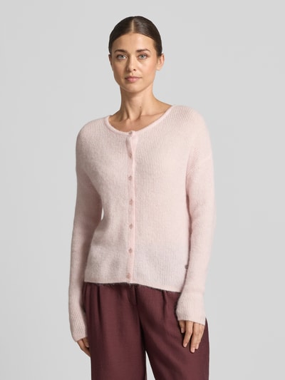 Frauenmodel trägt Strickjacke aus Alpaka-Mix von MOS MOSH in zartem Rosa, gerippter Rundhalsausschnitt, lockere Passform, Nahaufnahme Oberkörper.