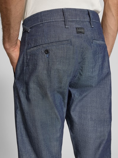 Mannenmodel draagt Tapered Chino in denimlook model 'Morry' van G-Star Raw, puur katoen, achterzakken, detailopname achterkant.