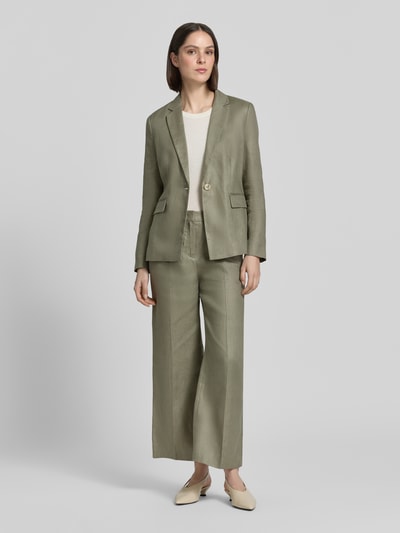 Frauenmodel trägt Leinenblazer aus Reinen Leinen mit Reverskragen von Christian Berg Woman Select-Kollektion, Farbe Olivgrün, Taillierte Passform, Knopfverschluss, Pattentaschen, glatte Textur, Ganzkörperansicht von vorne. Rückenlänge 68 cm, Brustweite 47 cm, Ärmellänge 62 cm bei Größe 36.